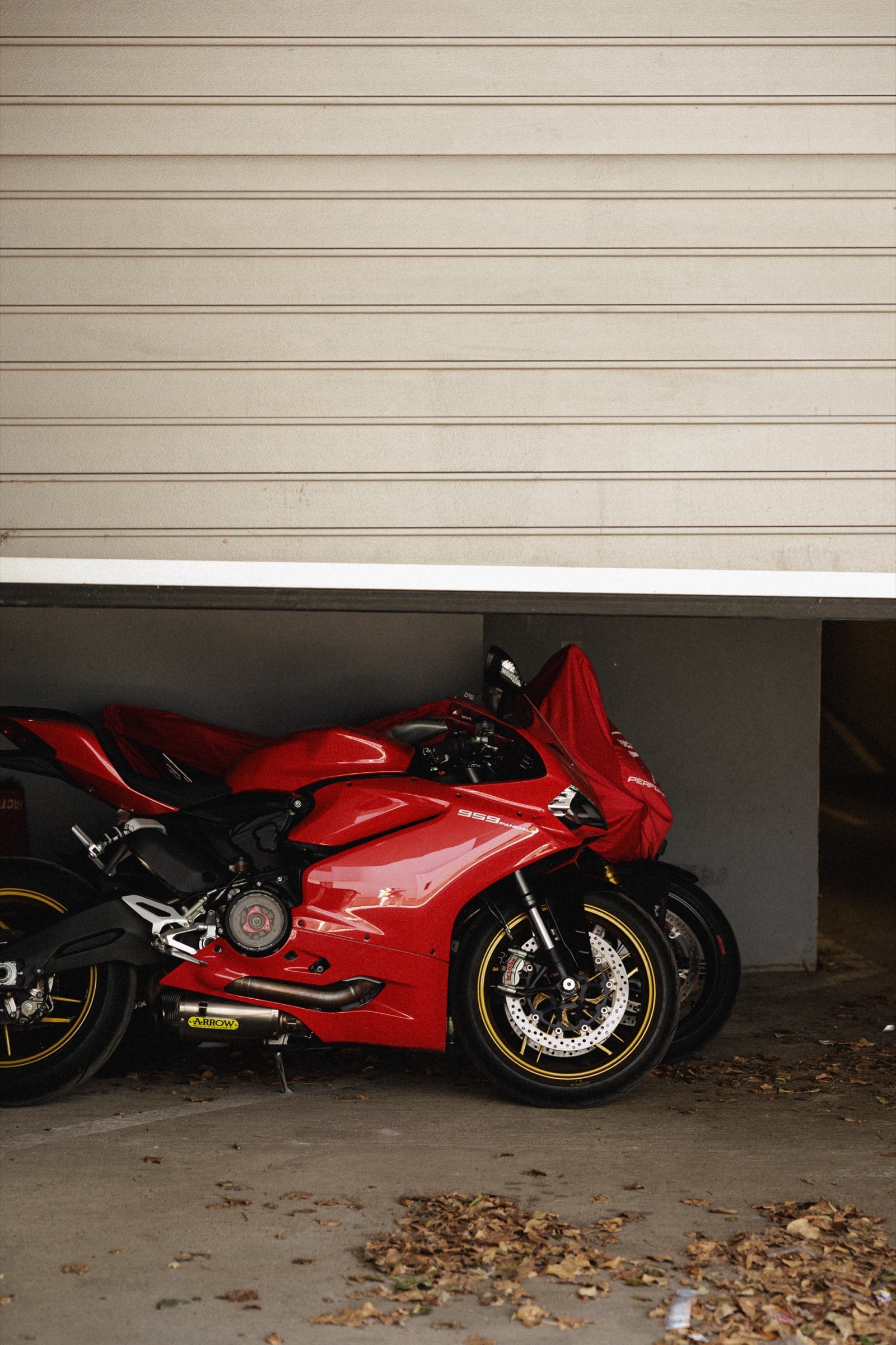 Červený motocykl Ducati pod zpola otevřenými vraty